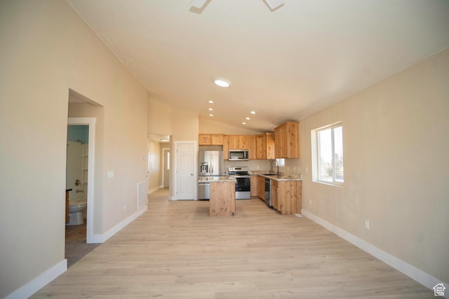 kitchen with sink, stainless steel appliances, a kitchen island, vaulted ceiling, and light wood-type flooring
