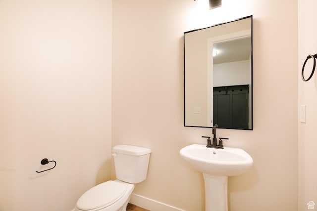 half bathroom with baseboards and toilet