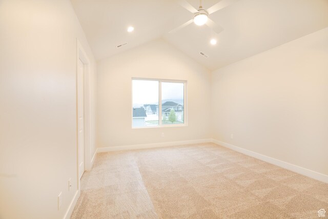 spare room featuring ceiling fan, light colored carpet, visible vents, baseboards, and lofted ceiling