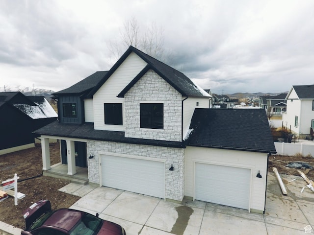 view of front of property with concrete driveway, a shingled roof, stone siding, and a garage