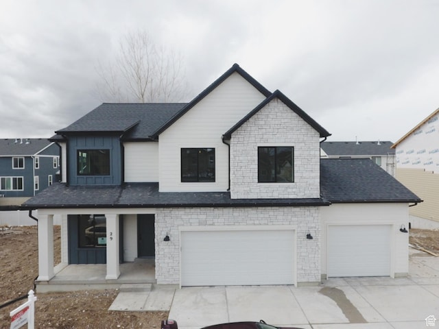 view of front of home featuring concrete driveway, an attached garage, stone siding, board and batten siding, and a porch