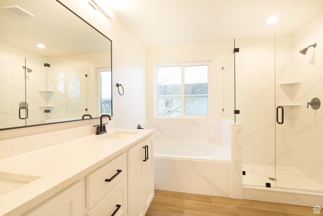 bathroom with visible vents, a marble finish shower, a sink, and wood finished floors