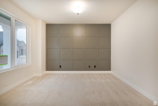 empty room with baseboards, light colored carpet, and visible vents