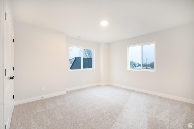 empty room with baseboards, recessed lighting, and light colored carpet
