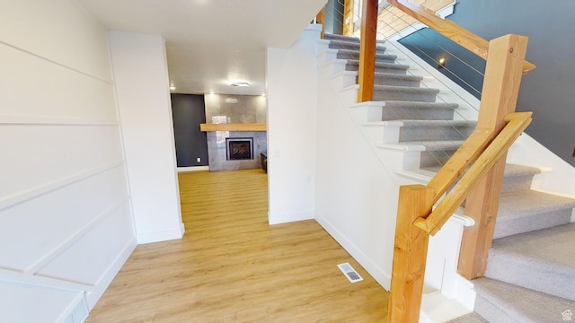 stairway with a tiled fireplace and hardwood / wood-style floors