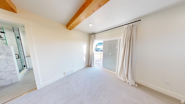 spare room with beamed ceiling and light carpet