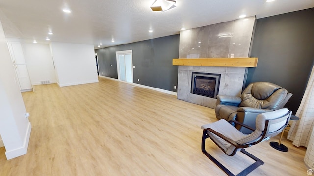 sitting room featuring a tile fireplace and light wood-type flooring