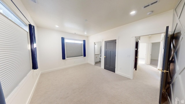 unfurnished bedroom featuring connected bathroom and light colored carpet