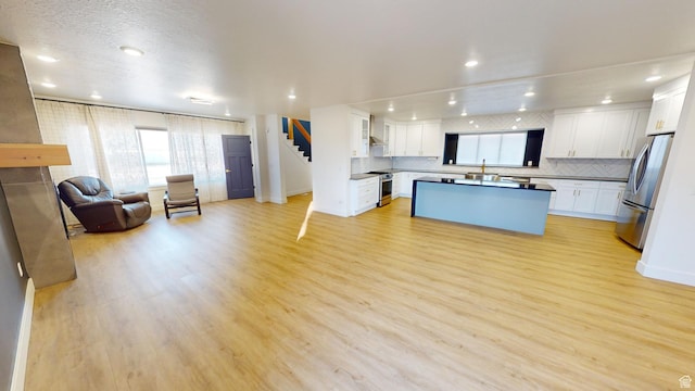 kitchen featuring stainless steel appliances, a center island, light hardwood / wood-style floors, and white cabinets