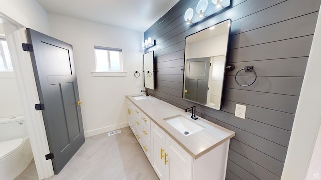 bathroom with vanity, wooden walls, and toilet