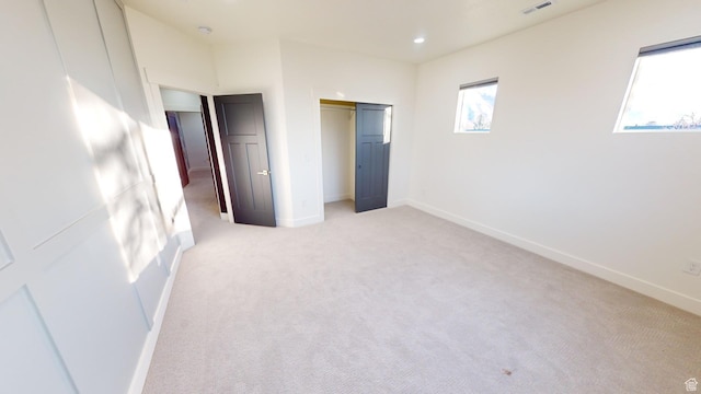 unfurnished bedroom with light colored carpet and a closet