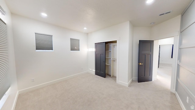 unfurnished bedroom with light colored carpet and a closet