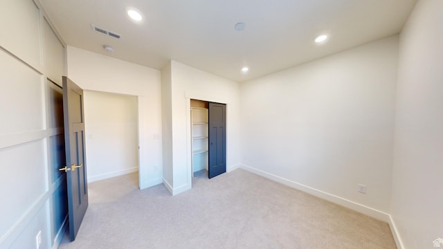 unfurnished bedroom with a closet and light carpet