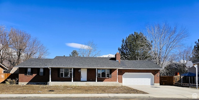 single story home featuring concrete driveway, fence, an attached garage, brick siding, and a chimney