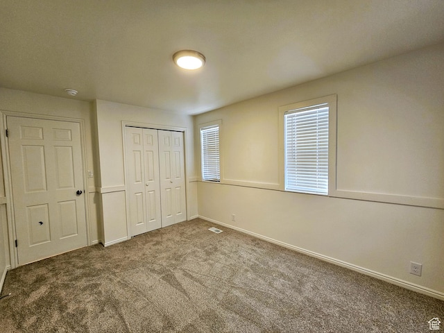 unfurnished bedroom featuring baseboards, carpet, a closet, and visible vents
