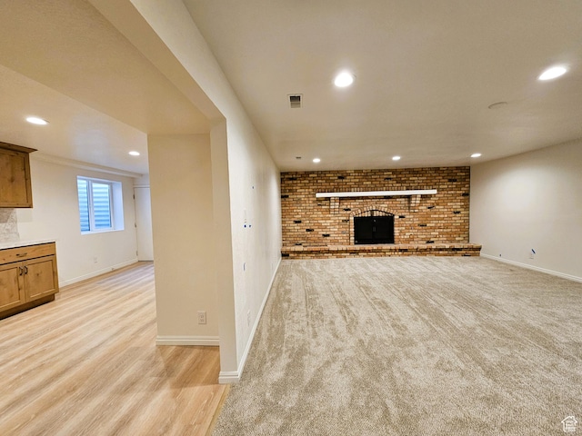 unfurnished living room featuring a brick fireplace, recessed lighting, baseboards, and visible vents
