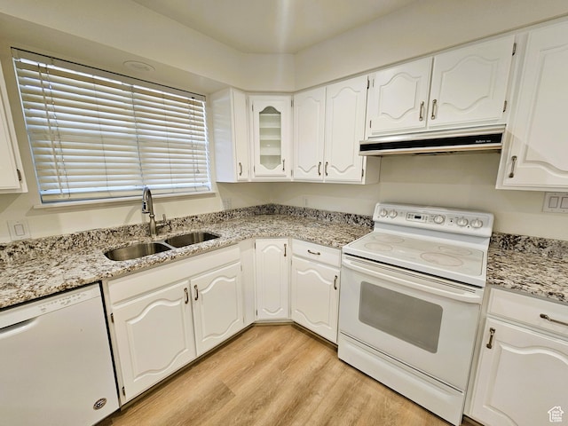kitchen with a sink, light wood-style flooring, under cabinet range hood, white appliances, and white cabinets