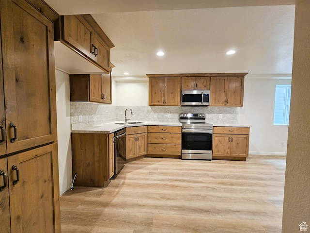 kitchen with a sink, light wood-style flooring, stainless steel appliances, and tasteful backsplash