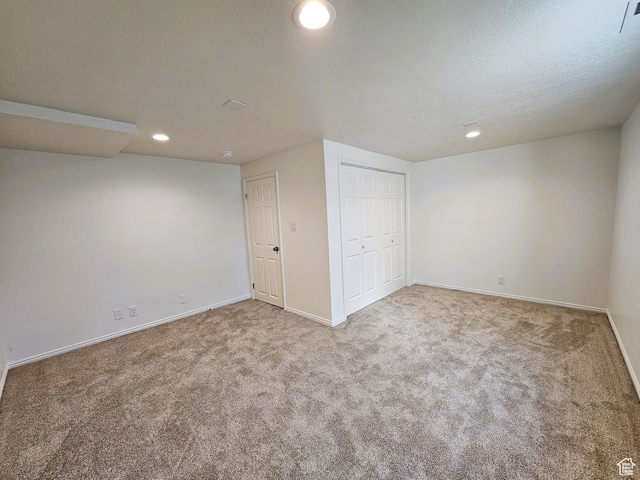 basement with carpet, a textured ceiling, baseboards, visible vents, and recessed lighting