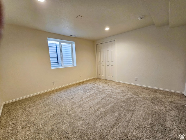 carpeted empty room with baseboards, visible vents, and recessed lighting