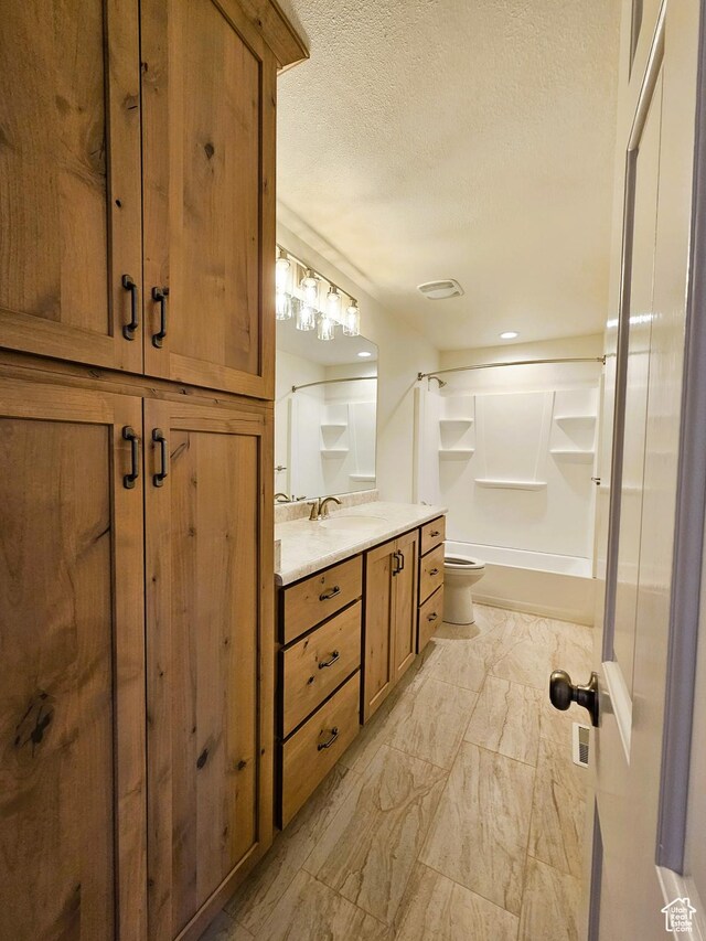 bathroom with toilet, vanity, a textured ceiling, marble finish floor, and visible vents