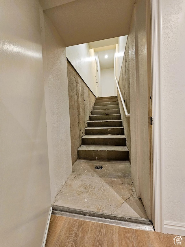 staircase with wood finished floors and a textured wall