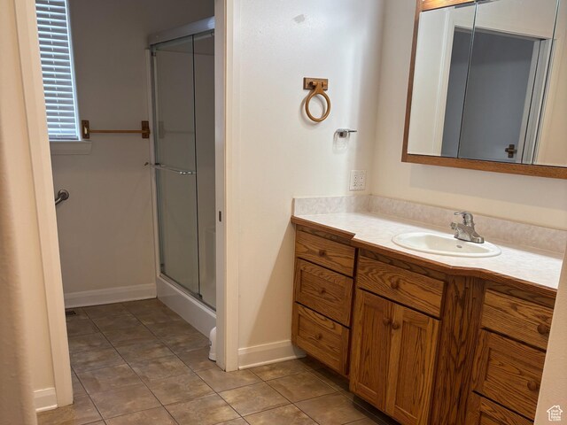 bathroom featuring tile patterned floors, vanity, baseboards, and an enclosed shower