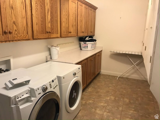 clothes washing area with tile patterned flooring, baseboards, cabinet space, and washing machine and clothes dryer