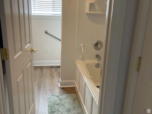 full bathroom featuring  shower combination, visible vents, baseboards, and wood finished floors