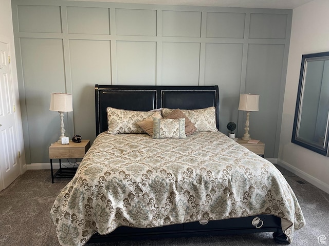 carpeted bedroom featuring baseboards and a decorative wall