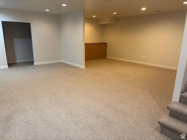 finished below grade area featuring recessed lighting, light colored carpet, stairway, and baseboards