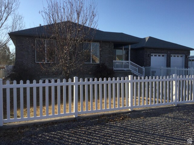 view of front of property with a fenced front yard, brick siding, and a garage