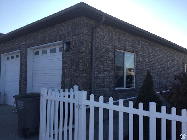 view of home's exterior featuring an attached garage, a fenced front yard, and brick siding