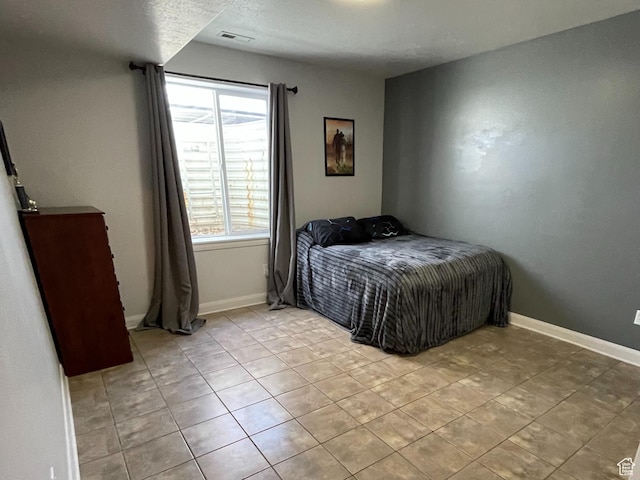 bedroom with visible vents, baseboards, and light tile patterned floors