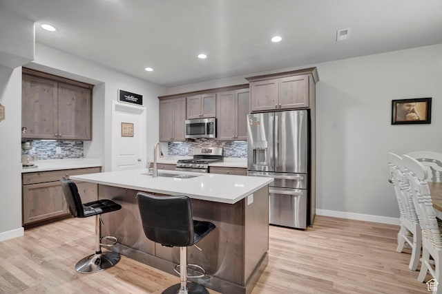 3529 W 4150 S, West Haven, UT 84401 - kitchen with appliances with stainless steel finishes, sink, a kitchen bar, a kitchen island with sink, and light hardwood / wood-style floors