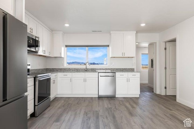 1980 W 3600 N, Beryl, UT 84714 - kitchen featuring appliances with stainless steel finishes, white cabinetry, light stone countertops, light wood-type flooring, and plenty of natural light