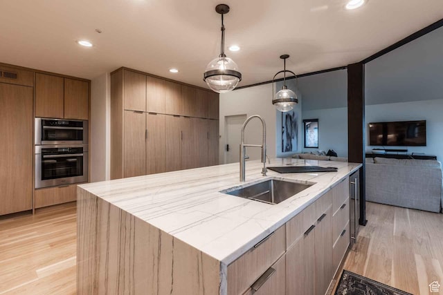 1555 Aerie Cir, Park City, UT 84060 - kitchen with sink, decorative light fixtures, a large island with sink, double oven, and light hardwood / wood-style floors
