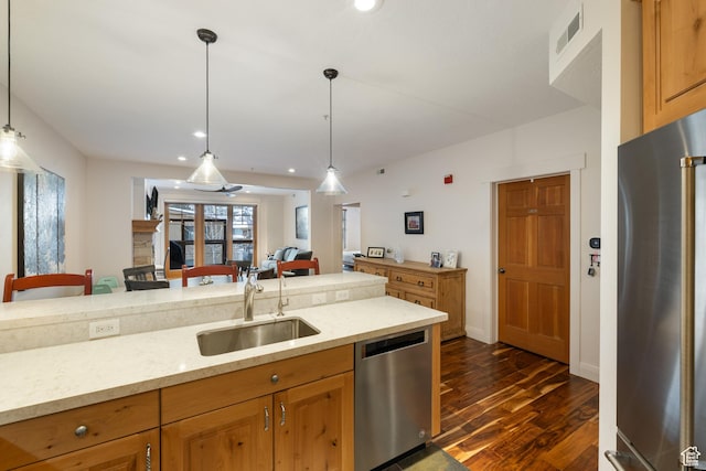 kitchen with light stone counters, appliances with stainless steel finishes, sink, and hanging light fixtures