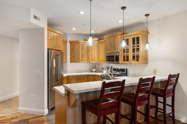 kitchen featuring stainless steel appliances, decorative light fixtures, a breakfast bar area, and kitchen peninsula