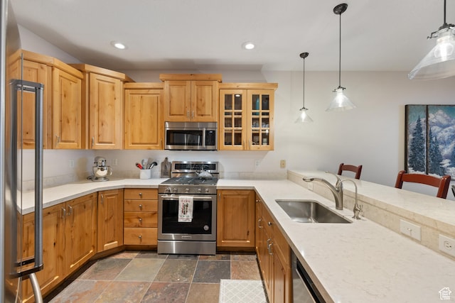 kitchen with hanging light fixtures, appliances with stainless steel finishes, sink, and a kitchen bar