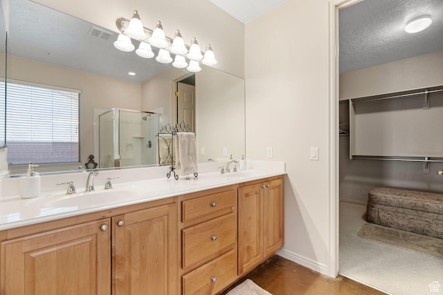 bathroom with a shower with door, vanity, and a textured ceiling