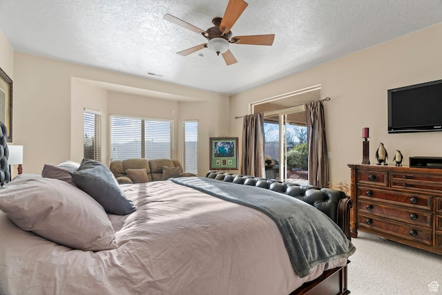 bedroom with ceiling fan, access to exterior, carpet floors, and a textured ceiling