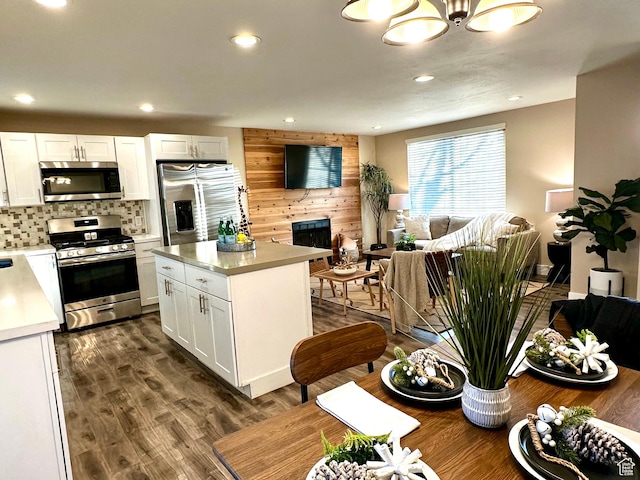 kitchen featuring stainless steel appliances, white cabinets, open floor plan, light countertops, and a center island