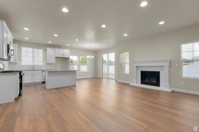 11878 S Golden Pine Ln, Riverton, UT 84065 - unfurnished living room with sink, a notable chandelier, and light hardwood / wood-style flooring