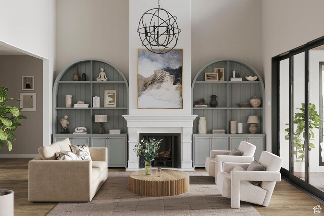 living area with built in shelves, a notable chandelier, wood finished floors, and a towering ceiling