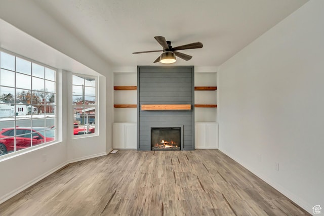 241 E Utah Ave, Tooele, UT 84074 - unfurnished living room featuring built in shelves, a large fireplace, baseboards, wood finished floors, and a ceiling fan