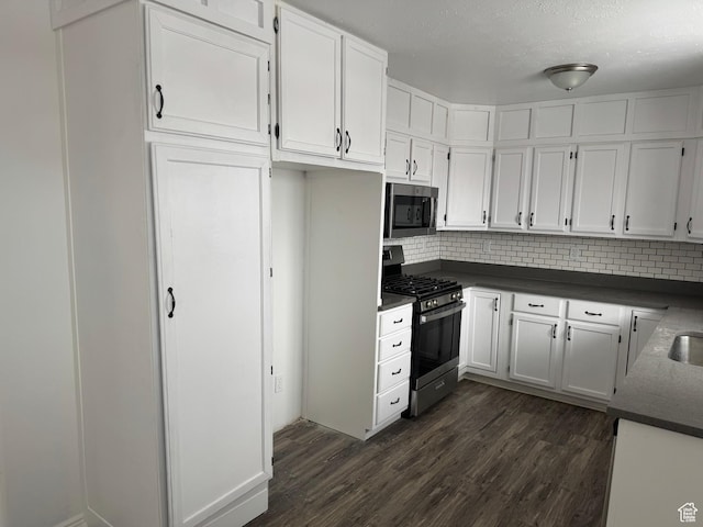 241 E Utah Ave, Tooele, UT 84074 - kitchen featuring dark countertops, decorative backsplash, stainless steel appliances, dark wood-style floors, and white cabinetry
