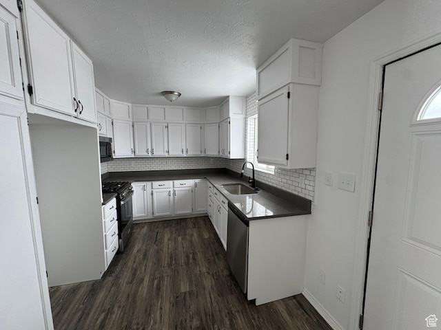 241 E Utah Ave, Tooele, UT 84074 - kitchen featuring dark wood finished floors, a sink, white cabinets, appliances with stainless steel finishes, and dark countertops