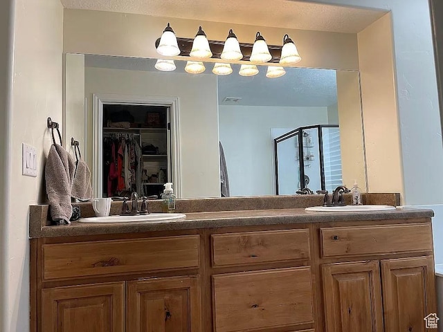 bathroom with vanity, a shower with shower door, and a textured ceiling