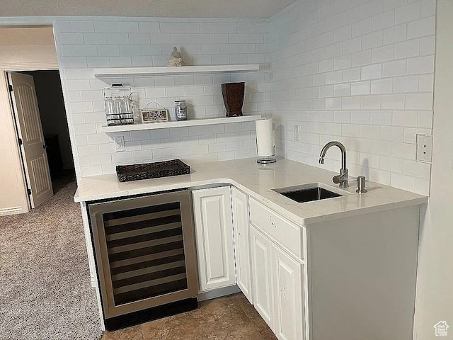 bar featuring sink, backsplash, wine cooler, light stone countertops, and white cabinets